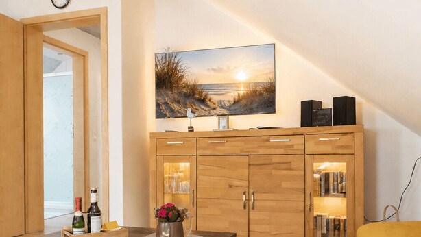 Un dormitorio tipo loft moderno con techo inclinado, un escritorio de madera, un sofá y un ventanal con vistas al exterior.