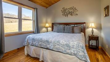 A bedroom with a bed, two bedside tables, a window, and a wall decoration.