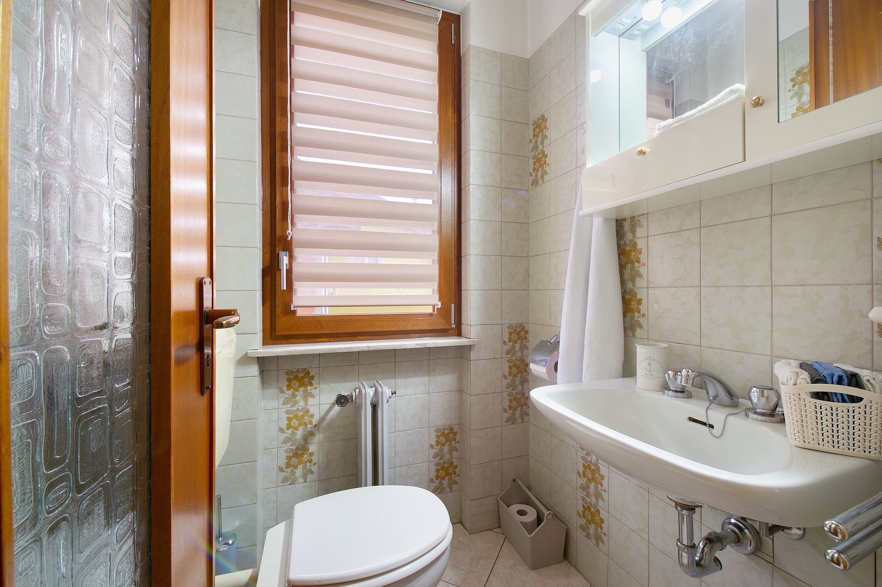 Ein Badezimmer mit Toilette, Waschbecken, Fenster und Duschbereich.