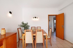 A dining area with a wooden table and chairs, a potted plant, and a wall-mounted light fixture.