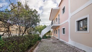 Un edificio con un camino empedrado, una pared de piedra y follaje.