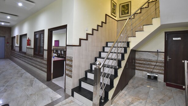 A hotel lobby with a marble floor, a staircase with black and white steps, and a fire extinguisher on the wall. - Hotel New Palace (Dalhousie)