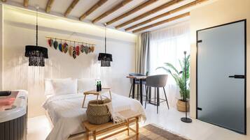 A modern bedroom with a bed, bedside table, and a desk with chairs.