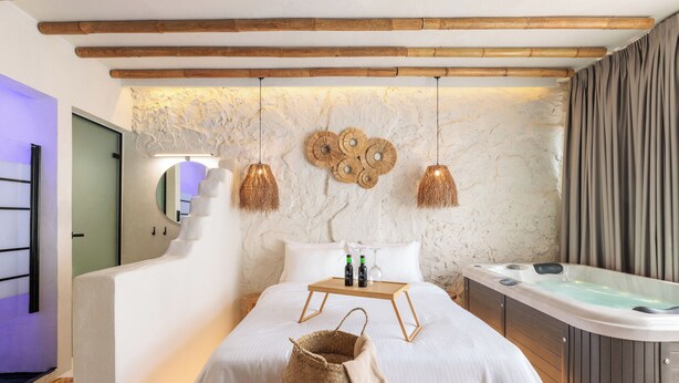 A bedroom with a bed, bedside table, and a hot tub.
