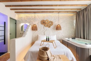 A bedroom with a bed, bedside table, and a hot tub. - Marabou Unique Stay (Thessaloniki)