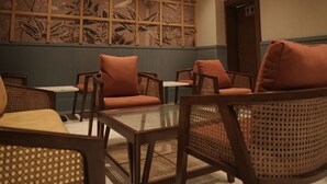 Una habitación con techo de madera, un ventanal con motivos florales, muebles de mimbre y una pequeña mesa.