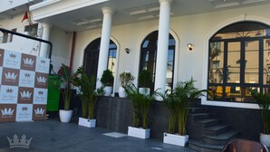Un edificio con columnas blancas, ventanas arqueadas grandes y plantas en macetas.