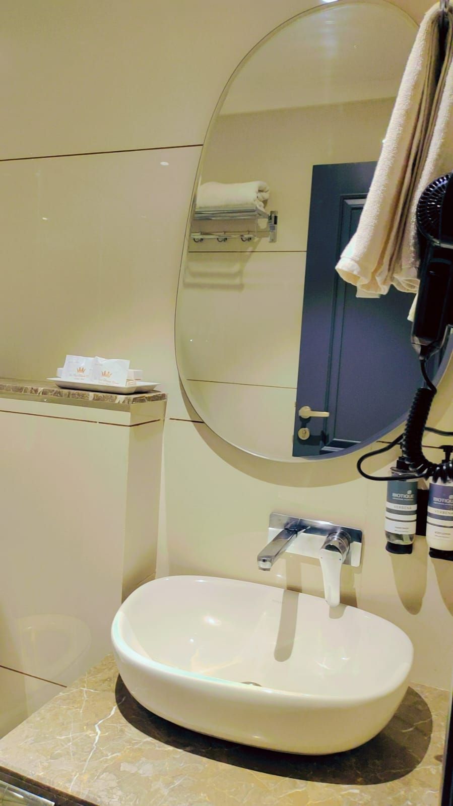 Ein Badezimmer mit rundem Spiegel, Waschbecken und Handtuchhalter.