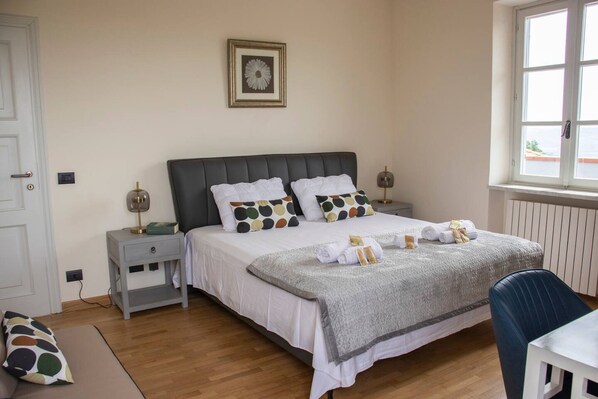 A neatly arranged bedroom with a bed, bedside tables, a chair, and a window. - Villa Magna With Pool and Park - Langhe Hills (Govone)