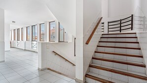 Un interior moderno con una escalera, pisos de baldosas y ventanas amplias.