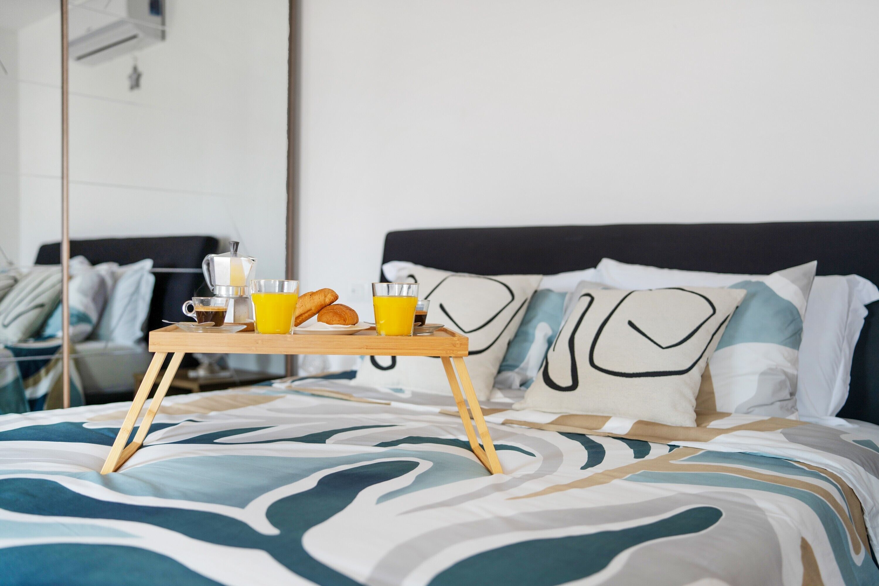 Ein Bett mit einem Tablett mit Frühstücksartikeln, darunter Croissants, Kaffee und Orangensaft.
