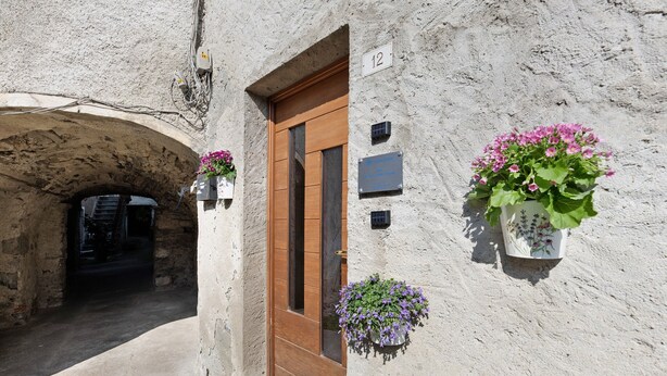 Un bâtiment avec une porte en bois, portant le numéro 12, et des jardinières fixées au mur.