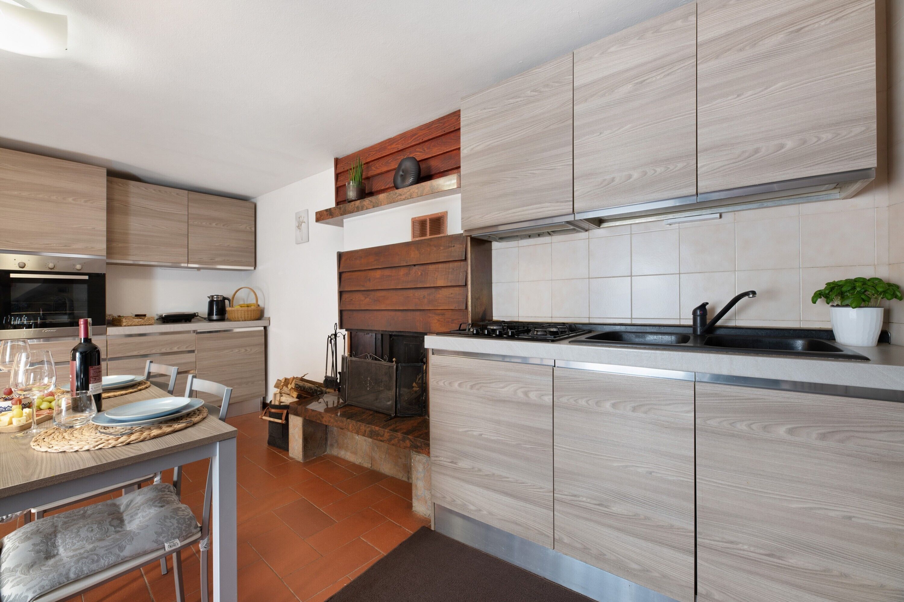 A modern kitchen with wooden cabinets, a built-in stove, and a dining area with a table and chairs.
