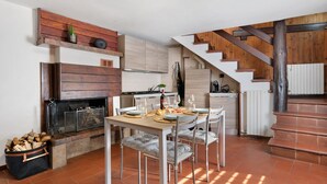 Une cuisine moderne avec une cheminée, une table à manger pour quatre personnes et un escalier menant à l’étage supérieur.
