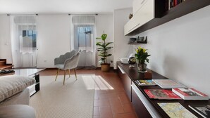 Un salon moderne comprenant un canapé, un fauteuil, une table basse, une bibliothèque et une plante en pot.