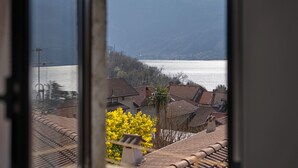 Une vue à travers une fenêtre donnant sur un quartier résidentiel, avec des maisons, une étendue d’eau et des montagnes en arrière-plan.