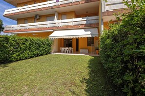 A multi-story building with a flat roof, a balcony, and a small outdoor seating area.