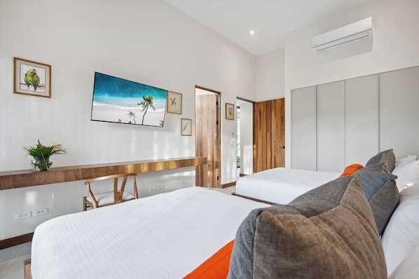 Habitación de hotel con dos camas, cabecera de madera, un cuadro de una playa y un armario grande.