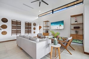 A modern living room with a sectional sofa, a dining table with chairs, and a large window with a view.