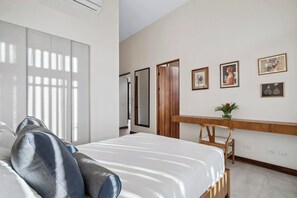 A bedroom with a bed, a wooden bedside table, and a wall with framed pictures.