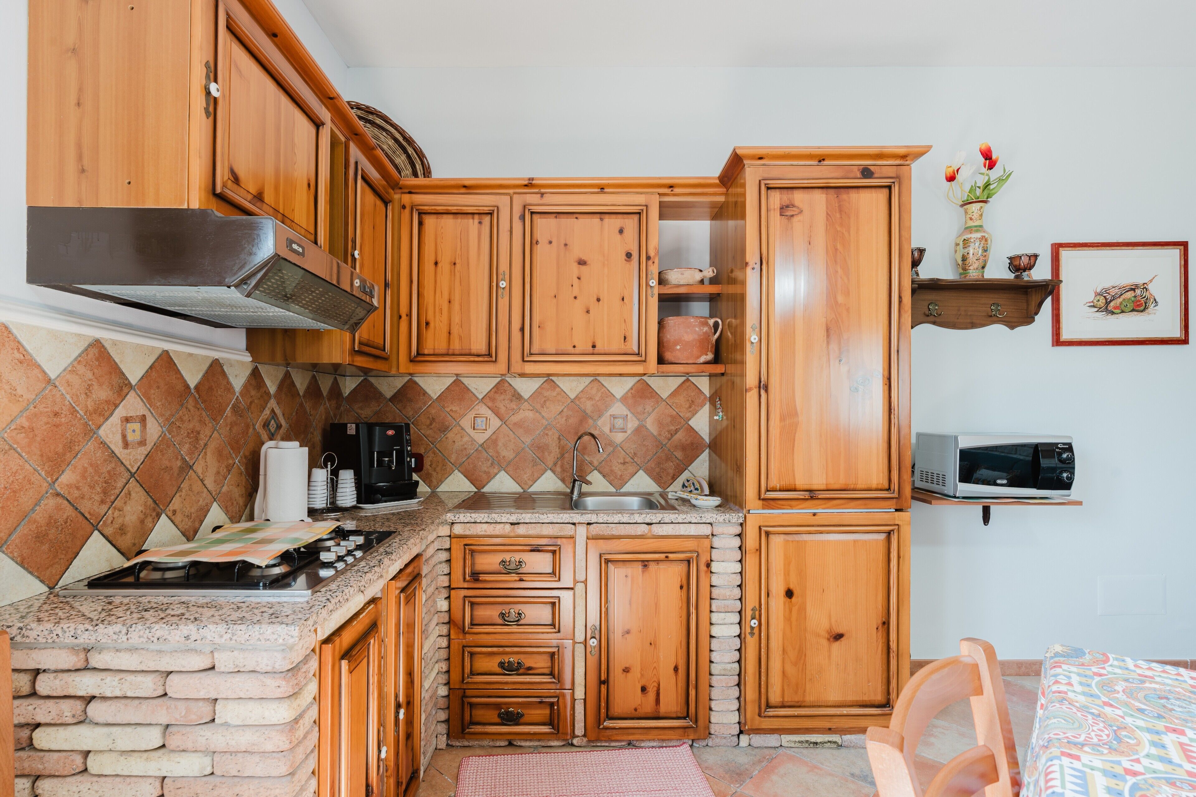 Une cuisine avec des meubles de rangement en bois, une cuisinière à gaz, un four à micro-ondes et un évier.