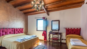 Una habitación con dos camas, techo de madera, candelabro, ventana y espejo.