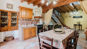 Una cocina rústica con armarios de madera, salpicadero de azulejos y un comedor con mantel estampado.