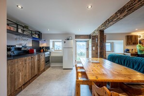 A modern kitchen with wooden cabinets, a dining table, and a refrigerator.