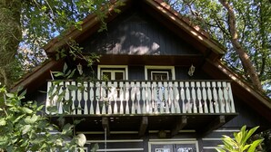 Una baita di legno con un balcone, un tavolo da pranzo e piante in vaso.
