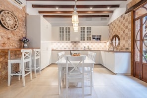 Una cocina con gabinetes blancos, techo de madera y una lámpara colgante.