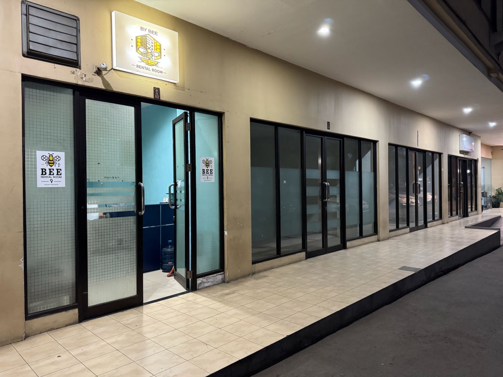 A building with a sign reading "BY BEE RENTAL ROOM" and a reception area with glass doors.