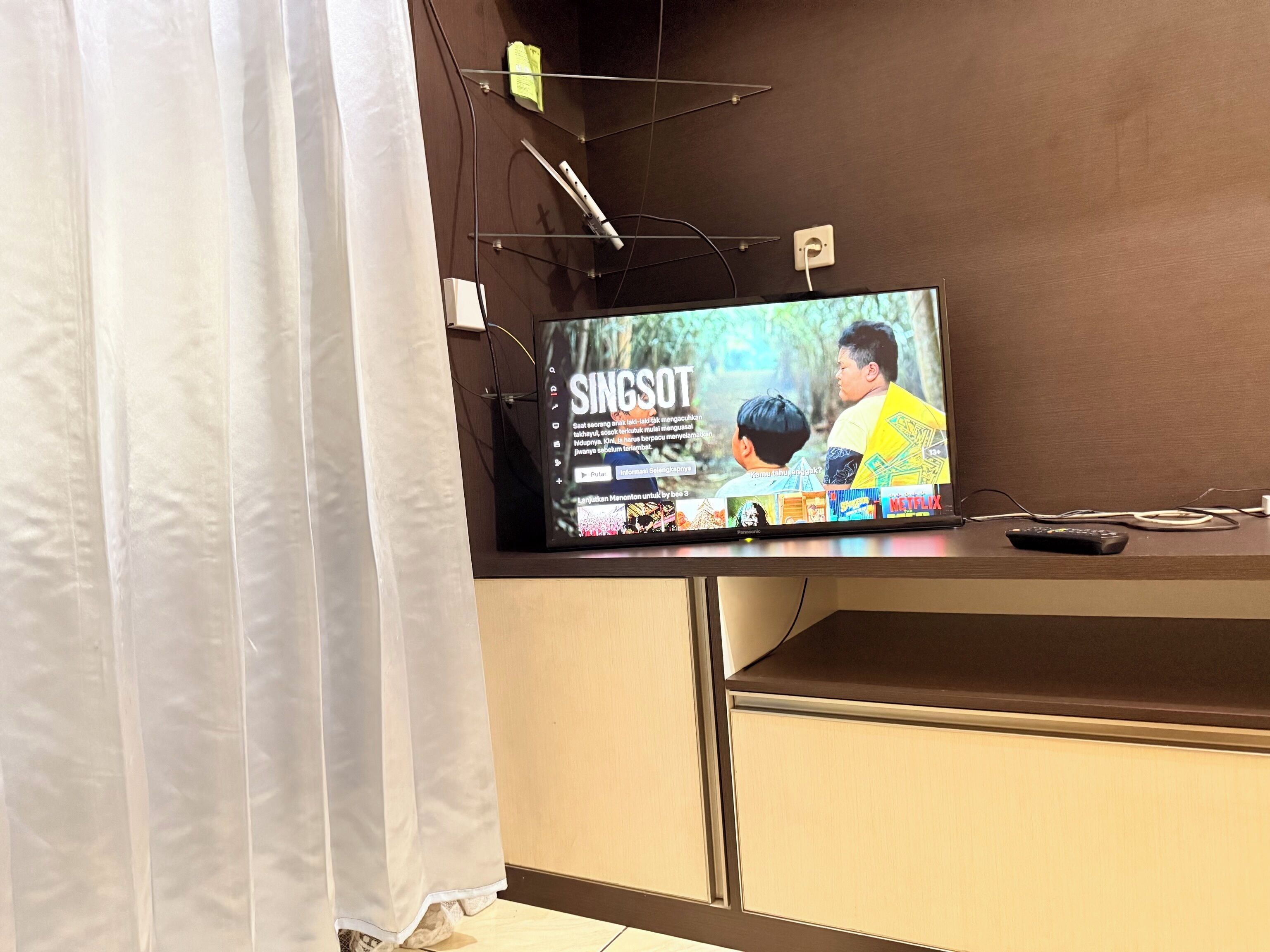 Un televisor montado en la pared con un control remoto a la derecha.