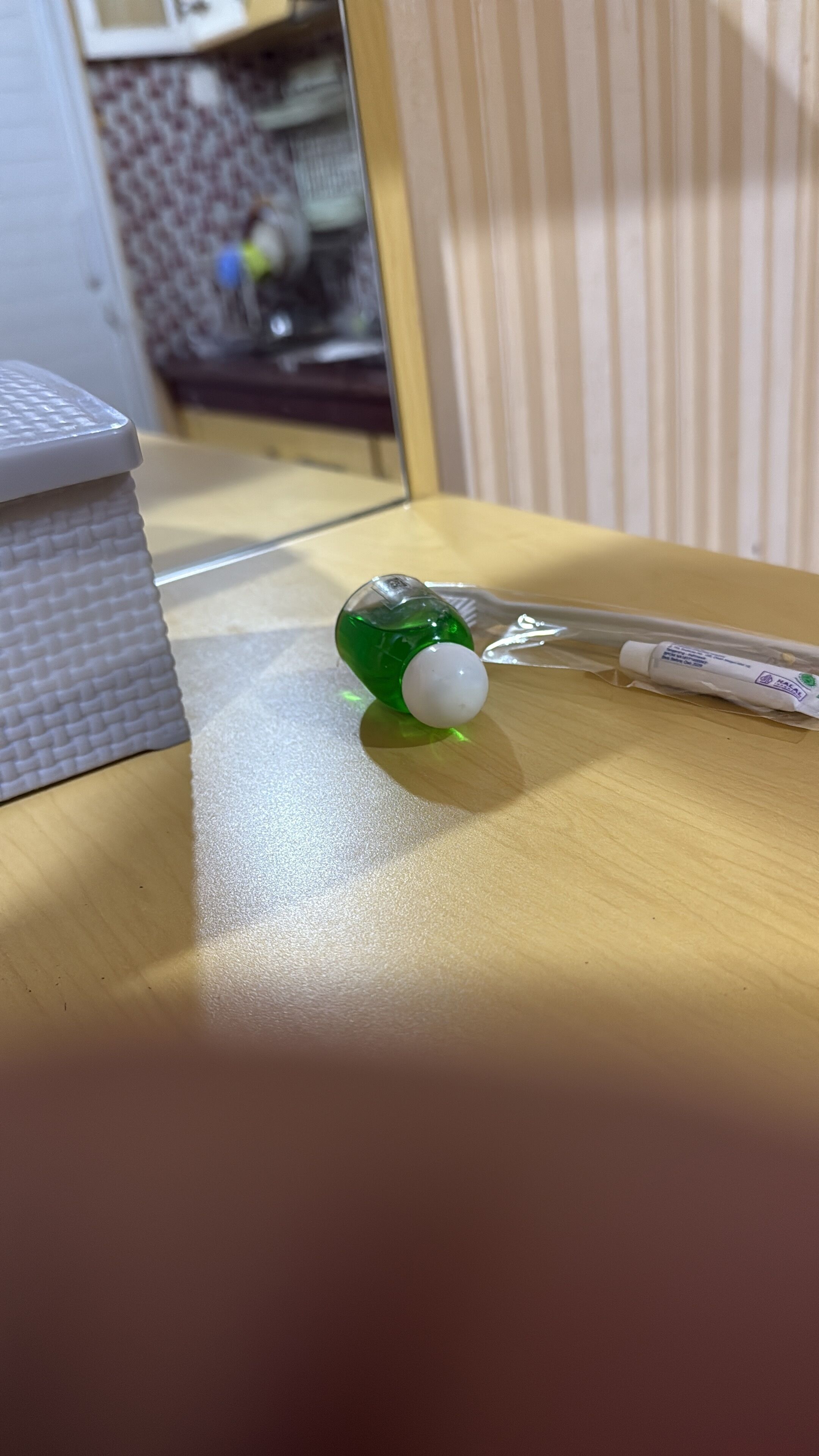 A green bottle with a white cap on a wooden surface.