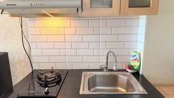 A kitchen with a black countertop, stainless steel sink, and a gas stove.