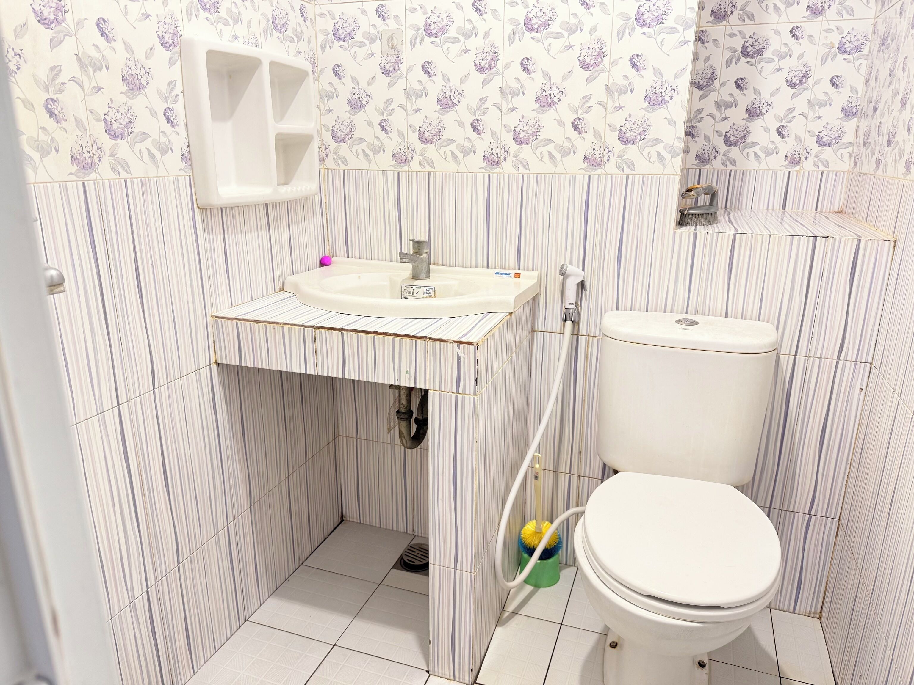 A small bathroom with a toilet, sink, and shower.
