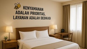 Habitación de hotel con cama, dos mesitas de noche con lámparas, un escritorio y una silla.