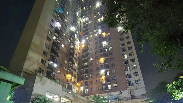 Un edificio de gran altura con varios pisos, balcones y ventanas iluminadas durante la noche.