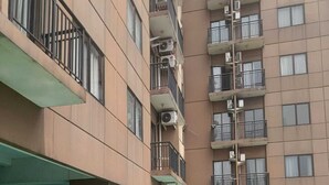 Una piscina con diseño de cuadros, rodeada por un edificio de varios pisos con balcones y unidades de aire acondicionado.