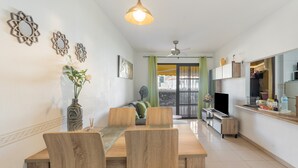 Un comedor con una mesa y sillas de madera, un florero con flores y un ventilador de techo.
