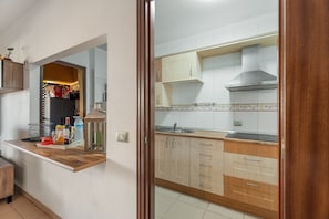 A kitchen with wooden cabinets, a stainless steel range hood, and a countertop with various items.