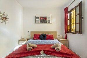 A neatly arranged hotel room with a bed, a nightstand, a wall-mounted mirror, and a window with curtains. - Vacation Apartment 'Costa Del Silencio Atlántico I' with Shared Pool, Private Terrace and Wi-Fi (Arona)
