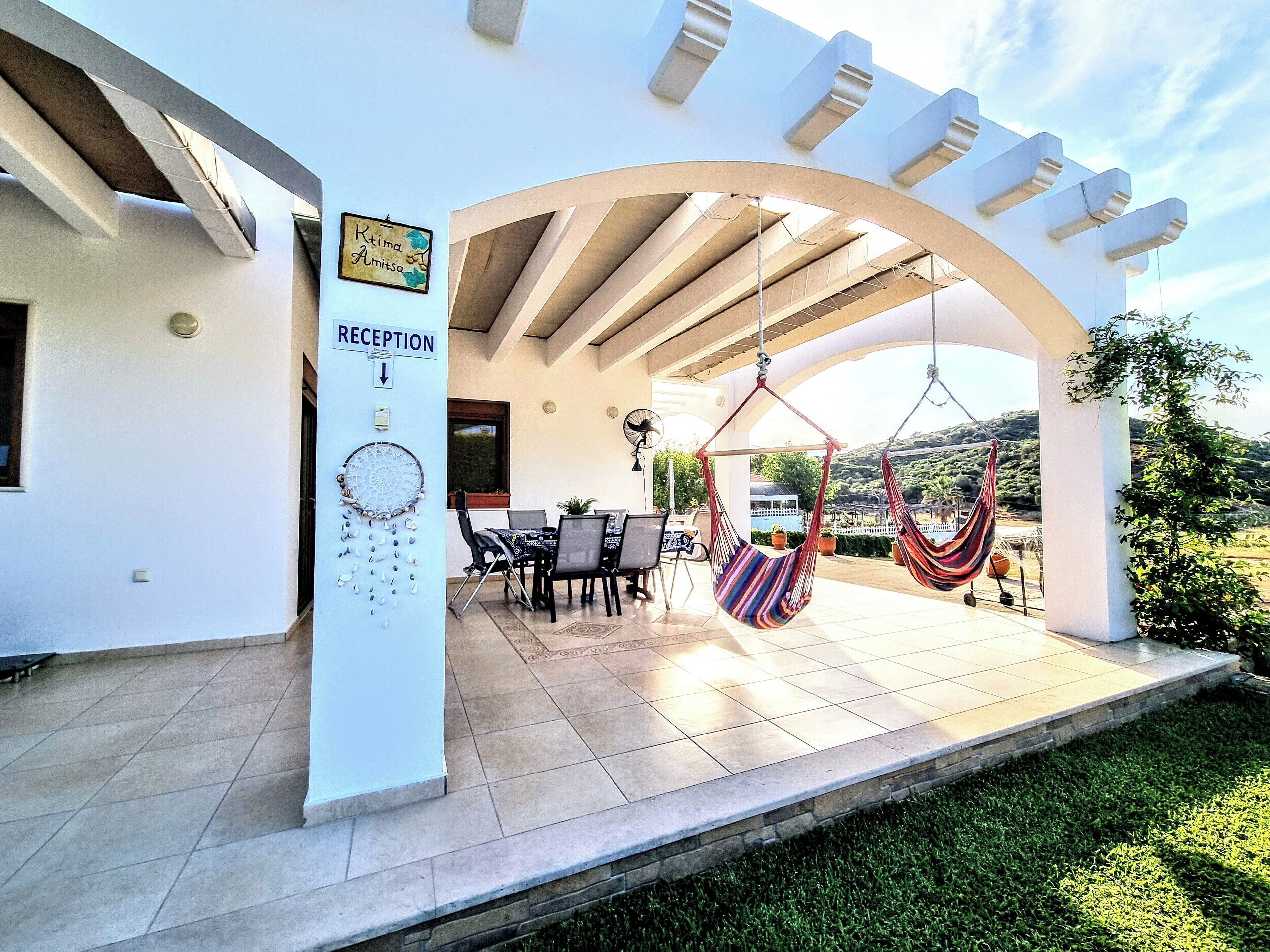 A reception area with a sign, a seating area with chairs and a table, and two hammocks hanging from the ceiling.
