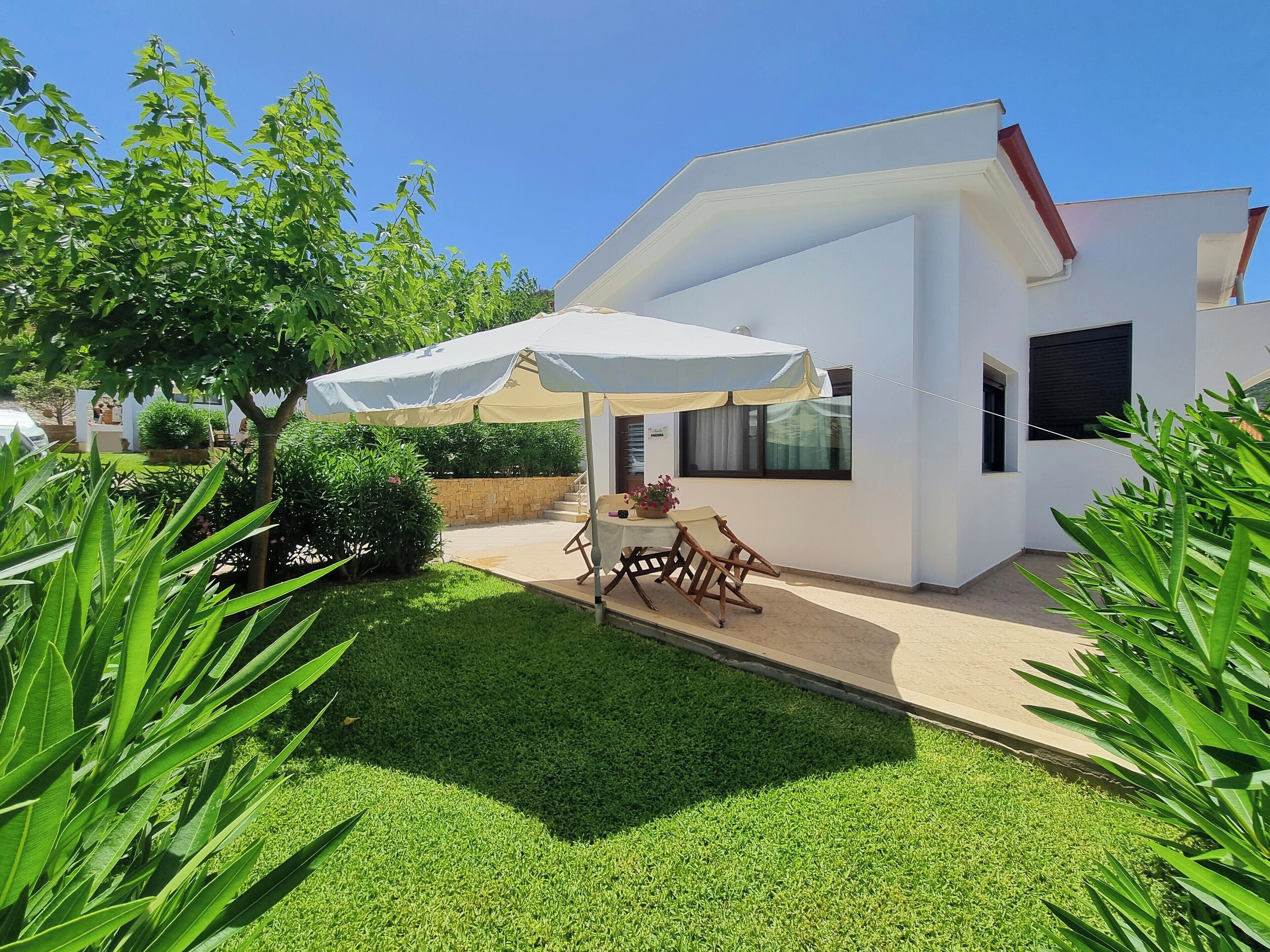 A modern house with a patio, a table, and chairs under a canopy.