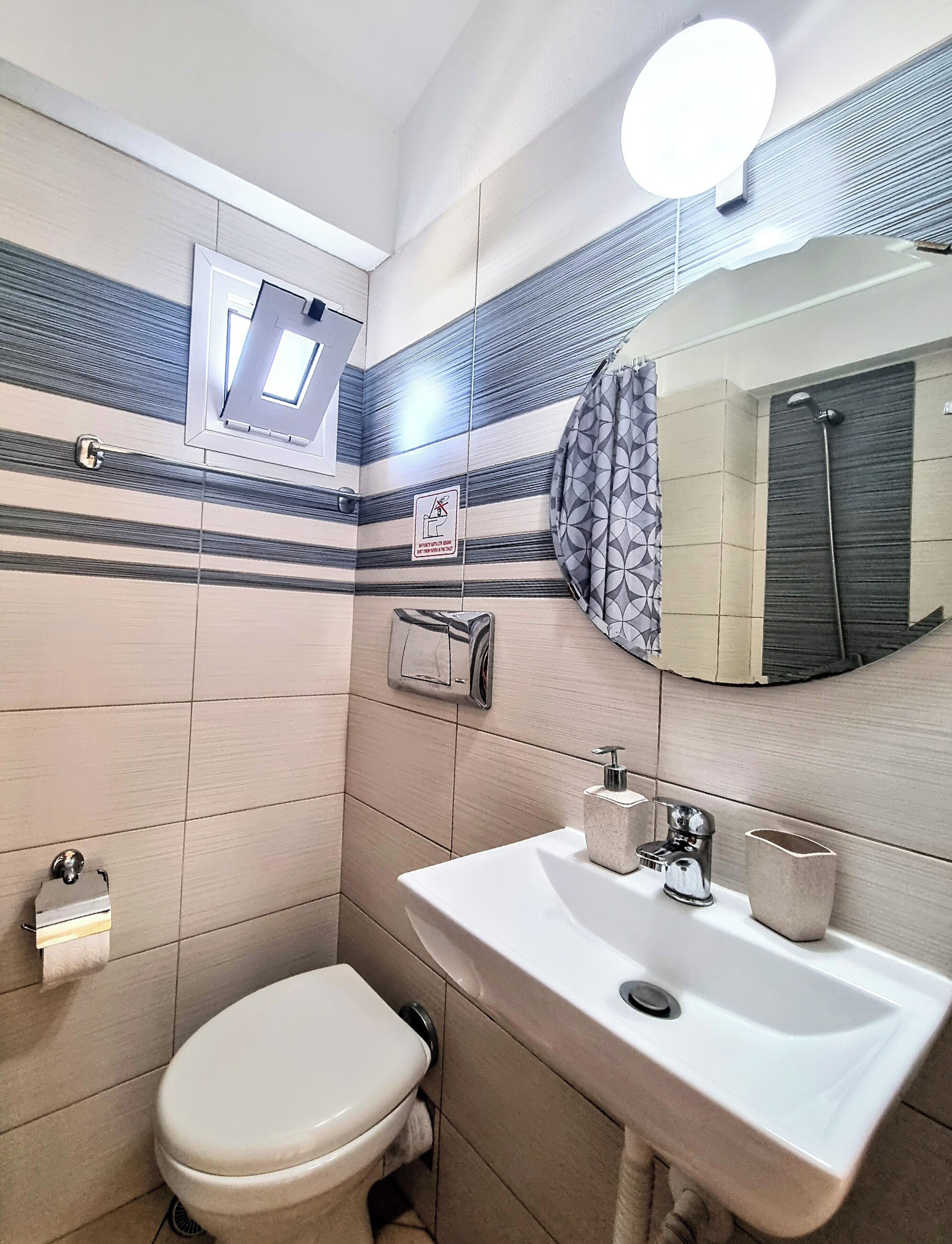 A bathroom with a toilet, sink, and shower.