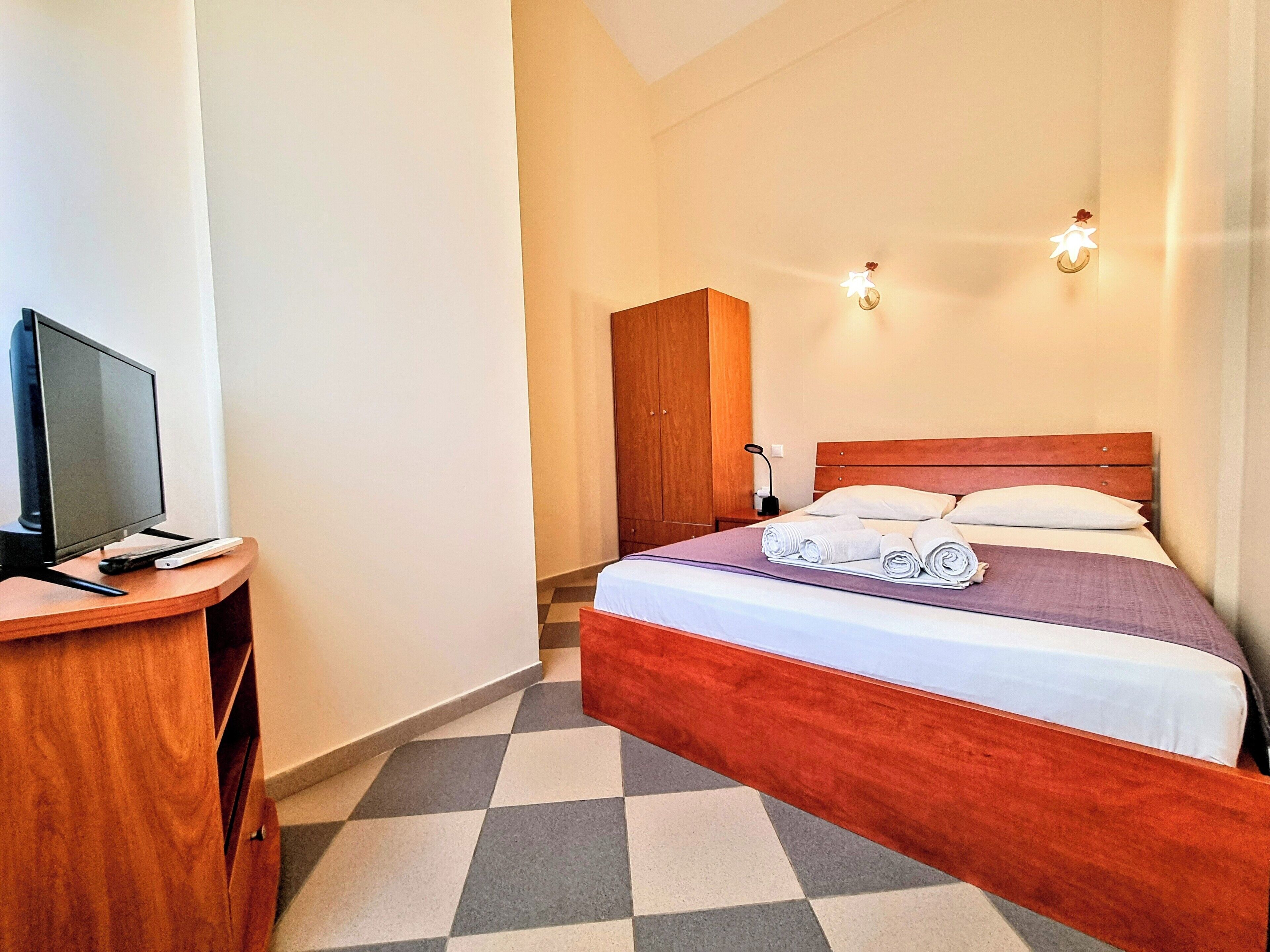 A hotel room with a bed, a TV, and a desk.