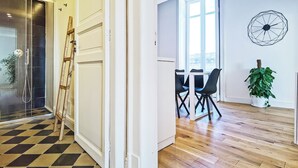 Un intérieur moderne avec un sol à carreaux, une échelle en bois, un coin repas avec des chaises et une grande fenêtre.