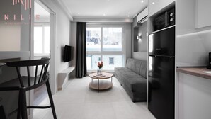 A modern kitchen with a built-in refrigerator, a dining area with a table and chairs, and a sofa. - Bonsai Studios & Apartments, Nilie Hospitality MGMT (Thessaloniki)