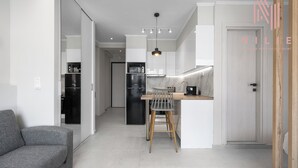 A modern kitchen with a dining area, a sofa, and a door leading to another room. - Bonsai Studios & Apartments, Nilie Hospitality MGMT (Thessaloniki)