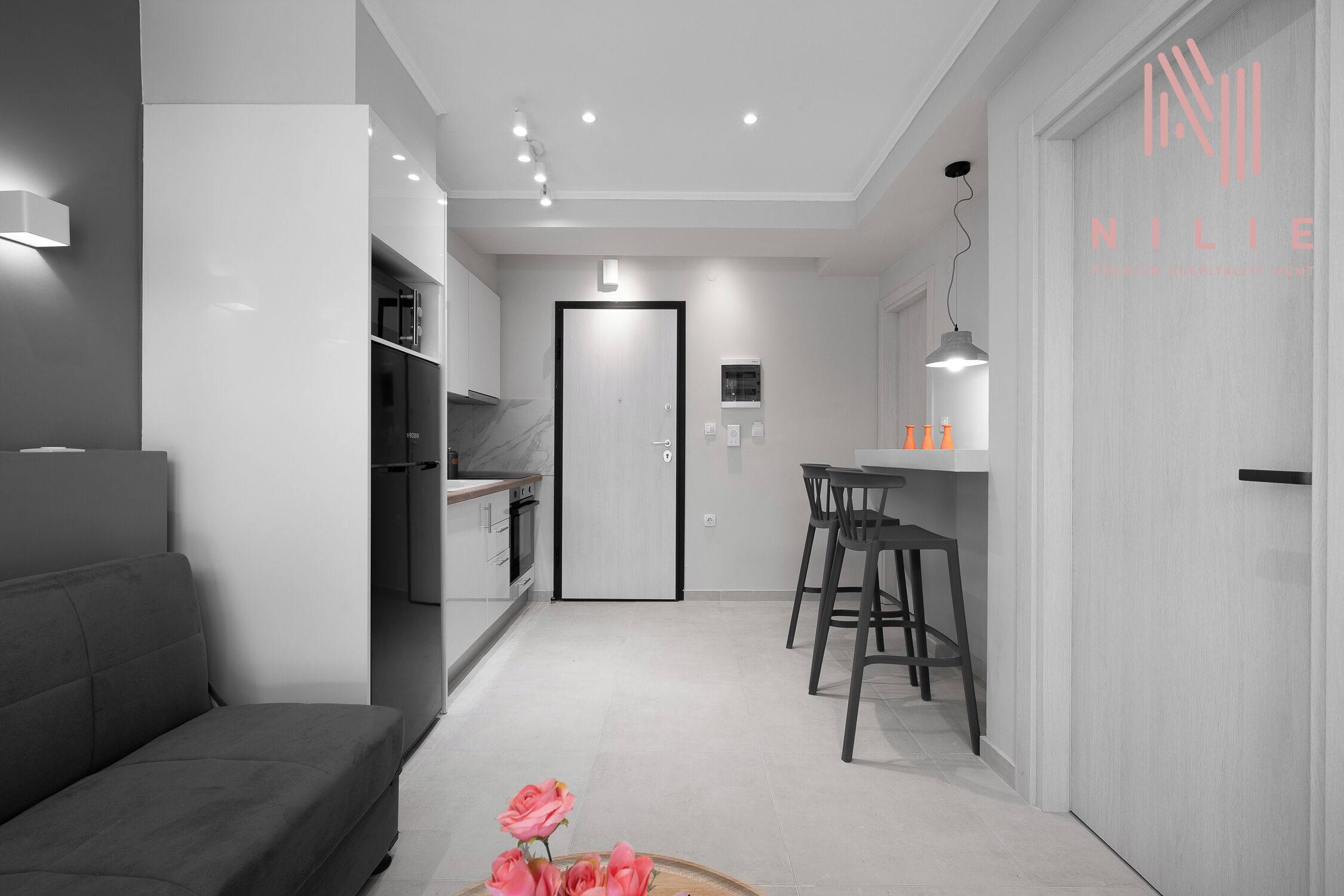 Una habitación de hotel moderna con sofá, un comedor con mesa y sillas, una cocina y una puerta que conduce a otra habitación.