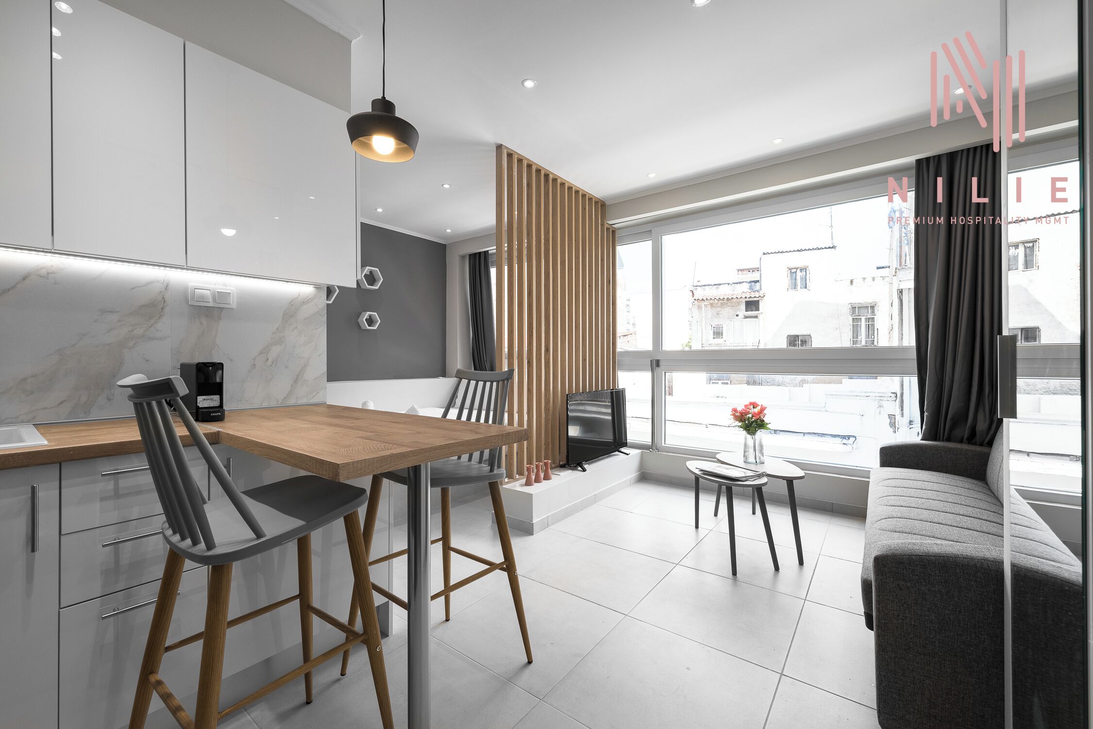 Una cocina moderna con una mesa y sillas de madera, horno empotrado y un ventanal con vistas a la ciudad.